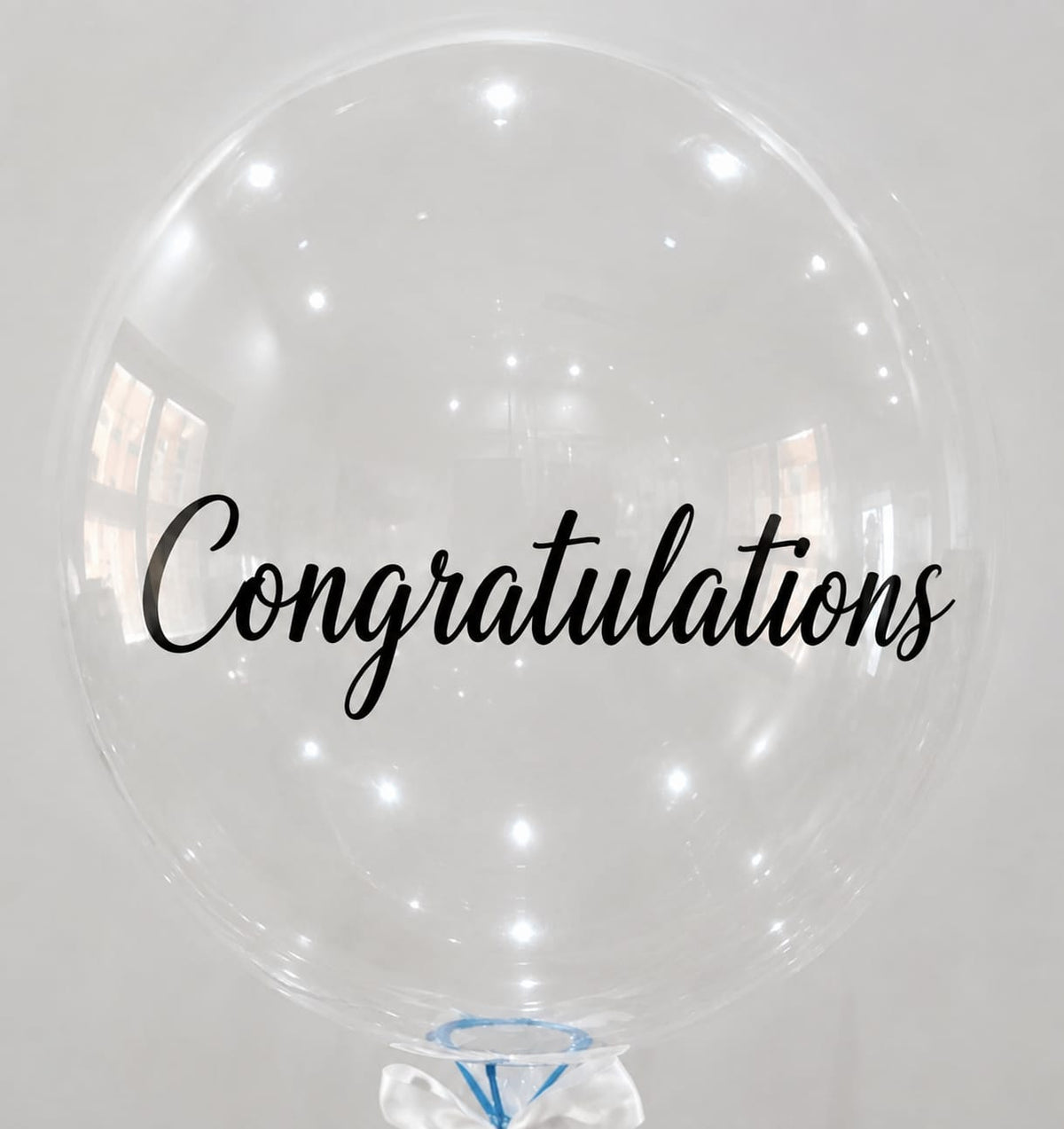 a large transparent balloon written congratultions on it.
