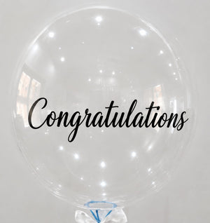 a large transparent balloon written congratultions on it.
