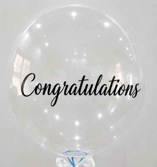a large transparent balloon written congratultions on it.